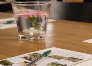 bild på penna, papper och en vas med en rosa blomma i konferenslokaler